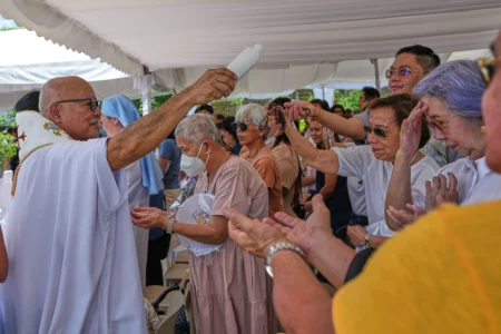 Le prêtre catholique, le père Dennis Paez, asperge d'eau bénite les pèlerins lors de leur visite à la Maison d'Éphèse, une réplique de la Maison de la Vierge Marie à Éphèse, en Turquie, dans la ville d'Alfonso, province de Cavite, Philippines, le 16 juillet 2026. (Crédit : Aaron Favila/AP.)